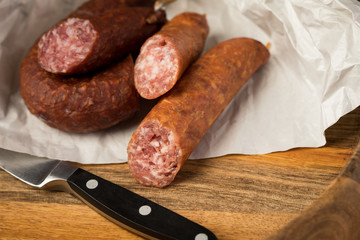 Ringwurst Salami und Bierbeißer Wurst in Wachspapier mit Messer auf Vesper Holzbrett