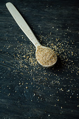 Wheat groats in a wooden spoon on a wooden dark background. Wooden spoon with wheat grains.