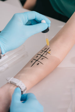 cropped view of doctor in latex gloves holding pipette with liquid near woman