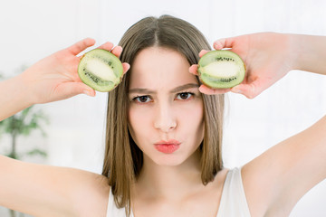Beauty woman holding slices of Kiwi fruit. Close-up portrait of young naked Caucasian girl is...