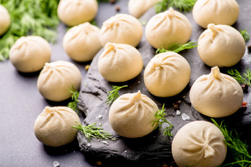 frozen khinkali and dumplings on a dark background with ingredients and spices. Semi-finished products