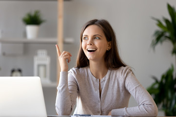 Young woman sitting at desk feels excited with good idea