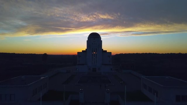 Drone approaching Radio Kootwijk, an abandoned building during sunset.