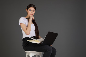 Upset unhappy businesswoman in white t-shirt leaning head on hand, sits on chair