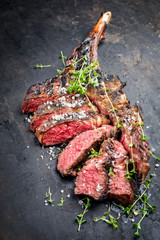 Traditional barbecue dry aged wagyu tomahawk steak sliced salt and herb as closeup on a rustic old...