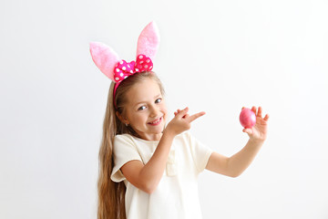 Obraz na płótnie Canvas Portrait of cute little five year old girl with long blond hair wearing easter bunny ears with pink polka dot bow, smiling and having fun on holy day. Isolated white backgroung, copy space, close up.