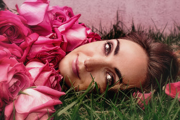 Portrait of a young woman in roses on the grass. Art portrait.