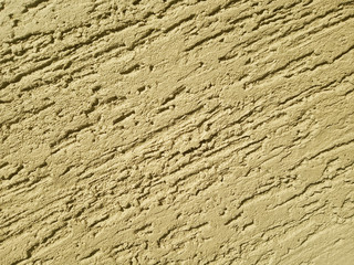 The texture of the stone wall painted with dry yellow plaster.
