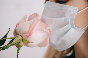 cropped view of woman in medical mask smelling rose