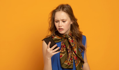 Fototapeta premium Portrait of young woman 20s in casual clothes speaking on smartphone while standing isolated over yellow background 