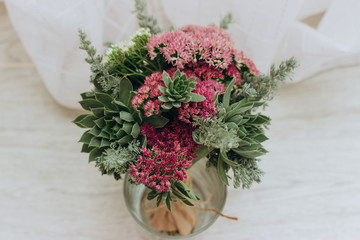 Beautiful wedding bouquet of succulents, crimson sedum and field grass.