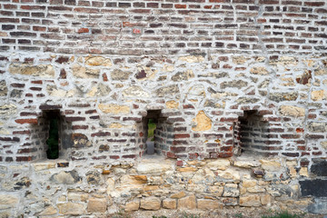 Brick wall of a old fortress with a window and grating
