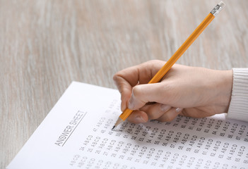 Student filling answer sheet at table, closeup