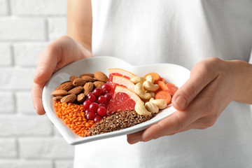 Woman holding plate with products for heart-healthy diet, closeup