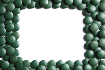 Frame made of green spirulina pills on white background, top view with space for text