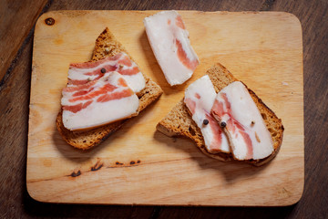 Lard sandwich with black bread and onions on a wooden board.