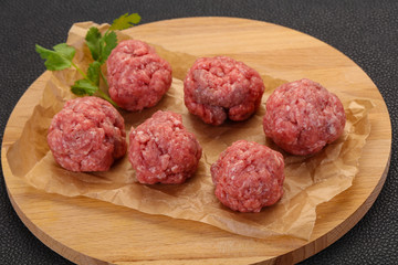 Raw meatball over wooden background