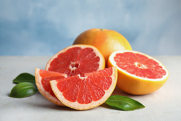 Fresh tasty grapefruits on table against color background