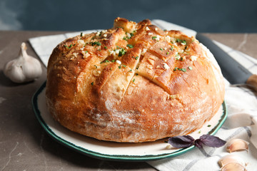 Plate with delicious homemade garlic bread on table