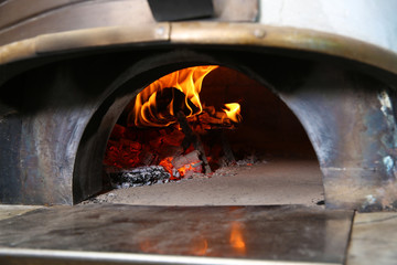 Fototapeta na wymiar Oven with burning firewood in restaurant kitchen