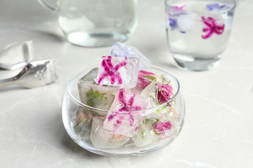 Obraz na płótnie Canvas Glass bowl of floral ice cubes on table