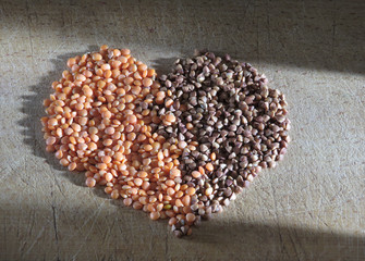 Lentils and buckwheat grains on a wooden board in the shape of a heart