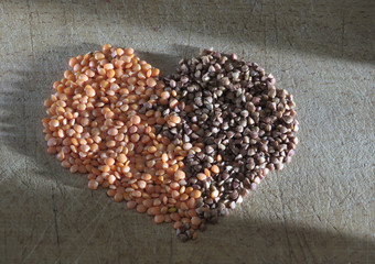 Lentils and buckwheat grains on a wooden board in the shape of a heart