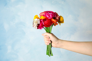 Woman holding bouquet with beautiful ranunculus flowers on color background