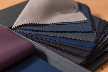 Close up of swatch book with various wool samples at tailor's workshop. Sartorial elegance.
