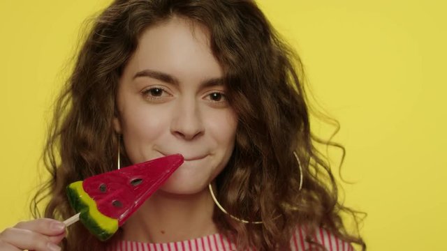 Young woman licking candy watermelon. Fashion model having fun with lollipop