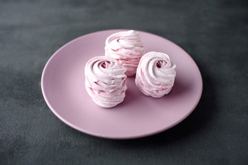 Homemade pink zephyr or marshmallow on pink plate with copy space on grey background. Marshmallow, Meringue, Zephyr. Valentine's or Mothers Day.
