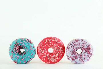 Vibrant composition of lush donut with colorful sprinkled icing, on bright background with a lot of copy space for text. Tasty but unhealthy food concept. Close up, flat lay, top view.