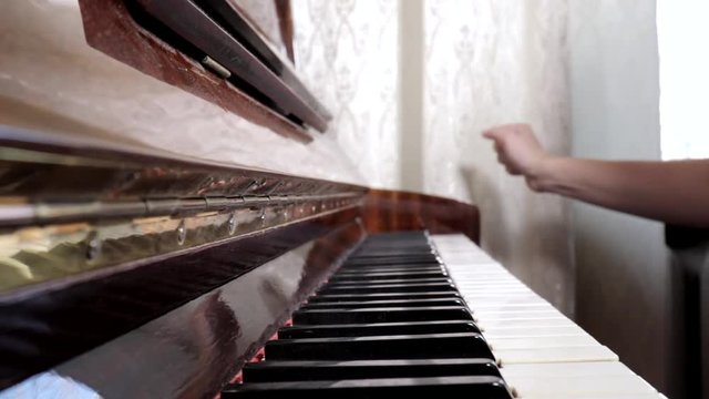 Hands of caucasian woman playing piano, close up, side view