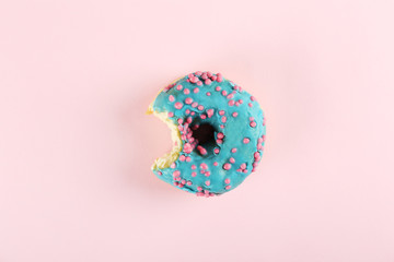 Vibrant composition of lush donut with colorful sprinkled icing, on bright background with a lot of copy space for text. Tasty but unhealthy food concept. Close up, flat lay, top view.