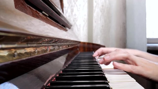 Hands of caucasian woman playing piano, close up, side view