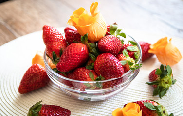 Fresh organic strawberries in a glass bowl on wooden table