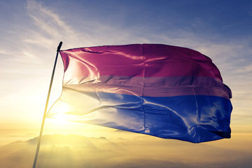 Bisexual pride flag waving on the top sunrise mist fog