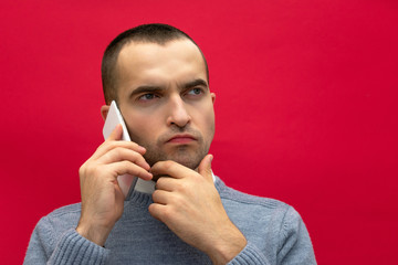 Portrait, man talking on phone, to the side looking up, front view, bright red background, close up