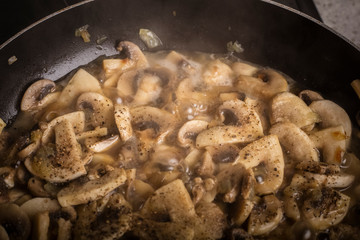 Cooking dishes from mushrooms with spices. Delicious champignons in boiling broth