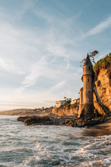 Obraz premium Waves in the Pacific Ocean and the Pirate Tower at sunset, at Victoria Beach, Laguna Beach, California