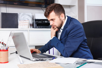 Fototapeta premium Confident man administrator of furniture store using laptop at workplace in showroom