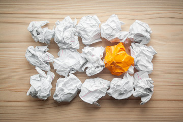 Heap of crumpled white paper balls with one different orange paper ball between them. Concept of think different, think out of the box, leadership.