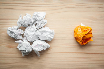 Heap of crumpled white paper balls with one different orange paper ball against them. Concept of think different, think out of the box, leadership.  Illustration of baiting.