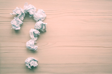 Question mark folded from white crumpled paper balls on wooden background. Inspiration, creativity, task solution concept. Symbol of creative thinking