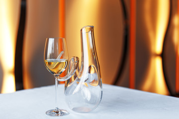 glass of wine and a decanter on a table with a white tablecloth.