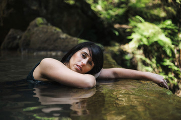 Beautiful, mature Portuguese woman relaxing in a hot spring spa in Caldeira Velha, Sao Miguel, Azores, Portugal.