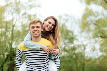 Fototapeta premium young beautiful girl on the back of a young man outdoors in summer 1