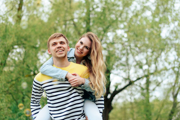 Fototapeta premium young beautiful girl on the back of a young man outdoors in summer 1
