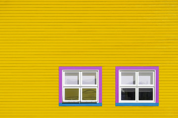 Pink and blue windows on yellow wall