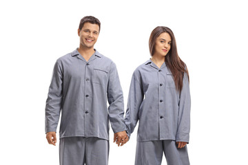 Young man and woman in pajamas holding hands